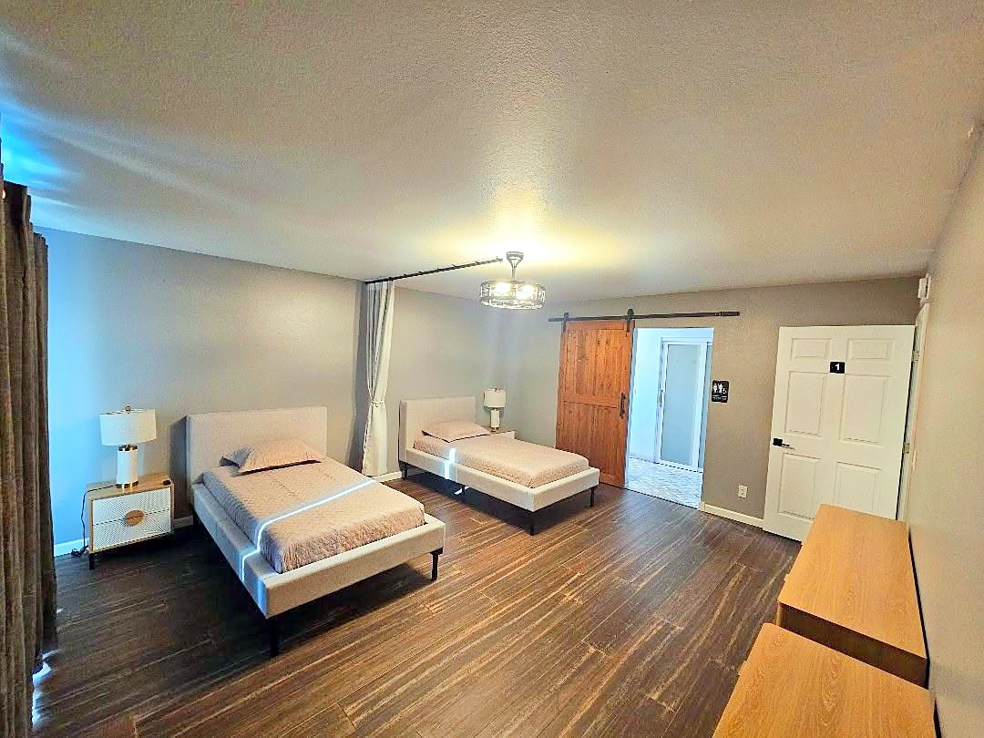 Shared bedroom with two single beds, nightstands, and a privacy curtain
