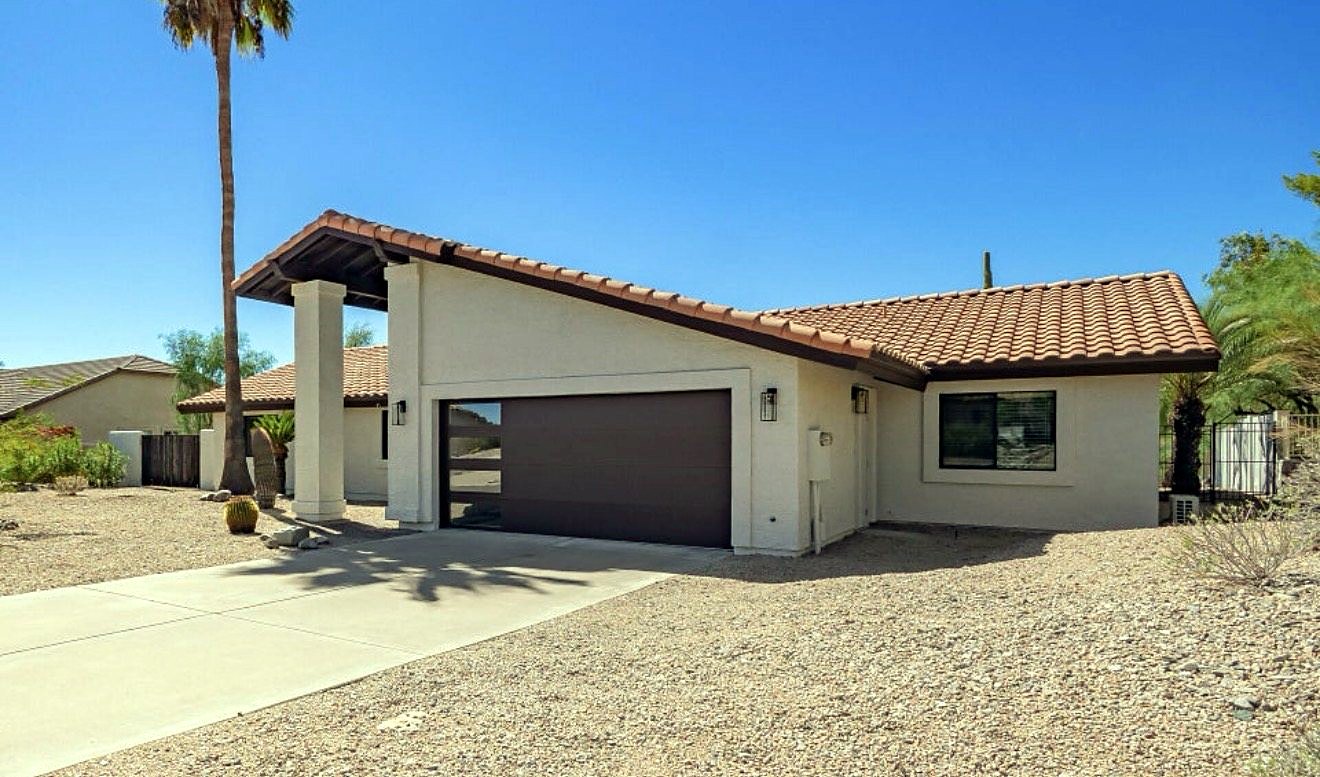 Front of the Desert Bloom home: a single-level house with a tile roof, palm tree, and desert landscaping