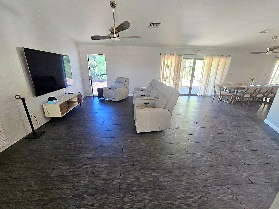 Living room with recliners, a large television, and sliding doors to the patio