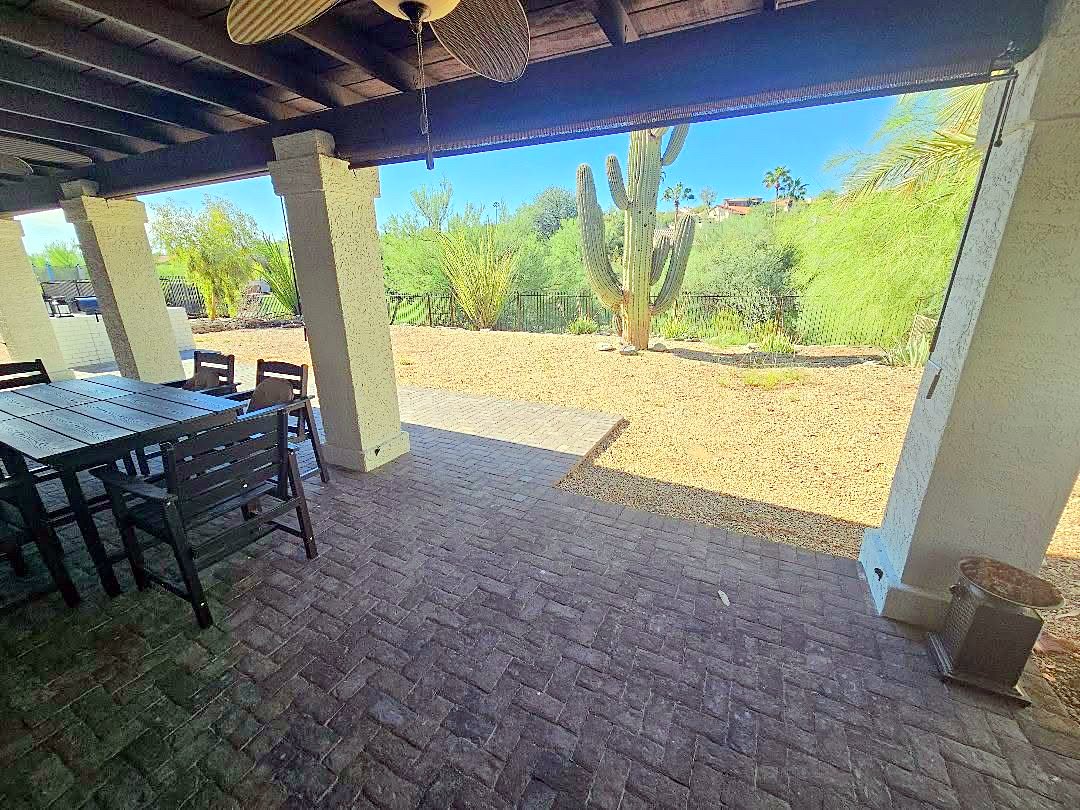 Covered patio with a dining table looking out at a saguaro and desert landscaping