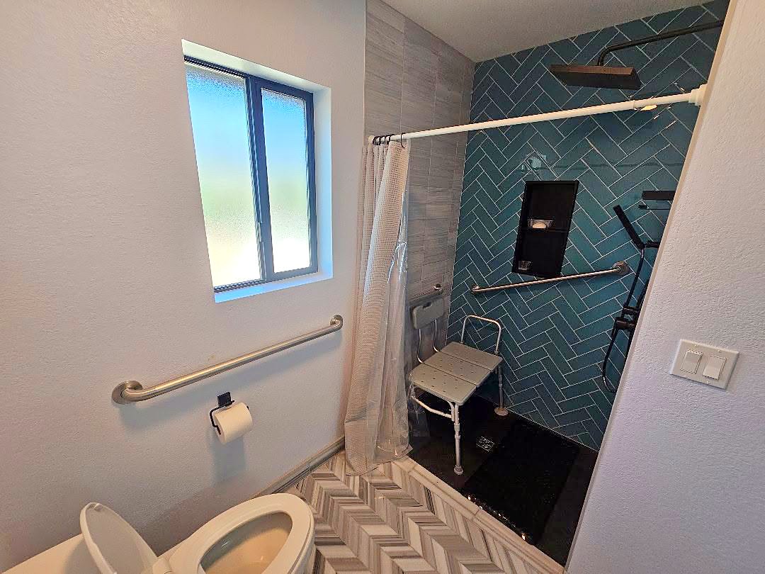 Walk-in tiled shower with a bench seat and grab bars